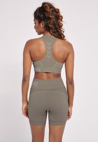 Olivgrön träningsset bestående av en ribbad sport-bh med racerback-design och matchande hög midja shorts med logotypdetalj.