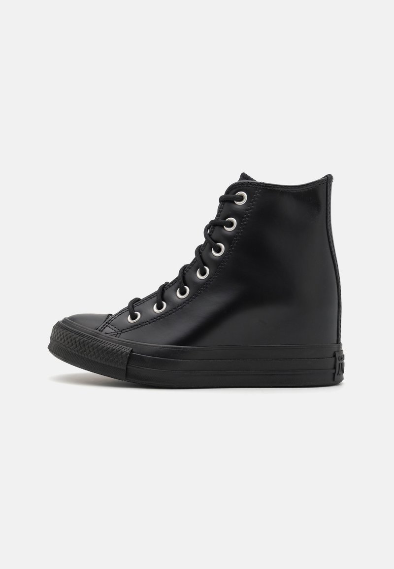 Czarny sneaker na wysokiej cholewce z sznurowaniem z przodu, gumową podeszwą i metalowymi oczkami, pokazany z profilu na białym tle.