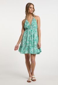 Rochie halter cu model paisley verde, cu bust pefit și fustă evazată, cu tiv volanat. Prezintă bretele ajustabile și stofă ușoară.