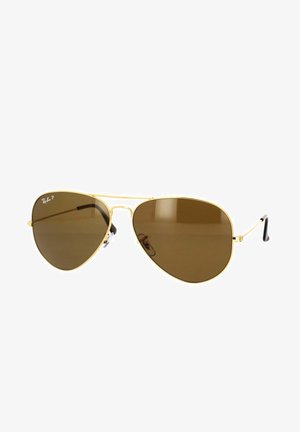 Occhiali da sole aviatori dorati con lenti marroni, montatura in metallo sottile e punte delle astine nere. Dotati di cuscinetti nasali per il comfort.