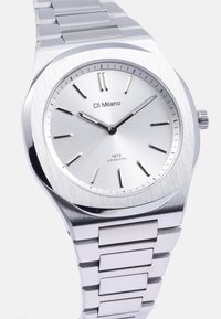 Reloj de acero inoxidable plateado con una esfera circular cepillada, marcas numéricas en las 3, 6 y 9 en punto, y un diseño de pulsera de eslabones.