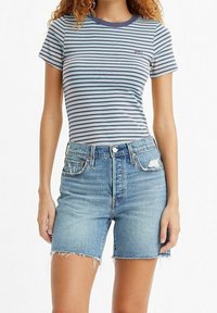 Randig t-shirt med korta ärmar, med blå och vita horisontella ränder och en marinblå ribbad krage som är kombinerad med högmidjade denimshorts.