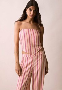 Strapless top og brede bukser i pink stof med lodrette striber i lilla, orange og creme; subtil tekstur; geometrisk udskæringsdetalje ved taljen.