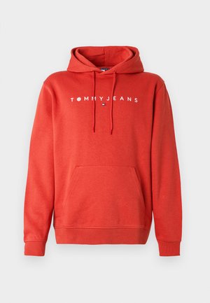 Punainen huppari, joka on valmistettu puuvillasekoitteesta. Siinä on kengurutasku, kiristettävä huppu ja valkoinen "TOMMY JEANS" -teksti rinnan kohdalla.