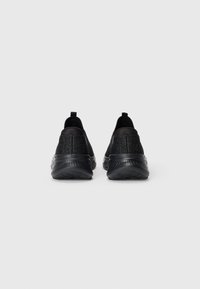 Black athletic shoes featuring a textured upper with a sleek design, a cushioned sole, and rear pull tabs for easy wear.