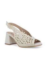 Sandalo beige con tacco e design a intaglio con dettagli in strass. Cinghia slingback con fibbia regolabile. Open-toe con un motivo geometrico.