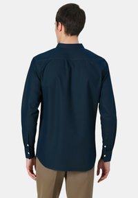 Camicia a maniche lunghe blu navy con colletto a punta, dettaglio su cucitura posteriore e polsini con bottone. Realizzata in tessuto leggero e morbido.