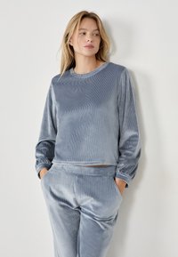 Conjunto de loungewear de pana gris que incluye una camiseta de manga larga con cuello redondo y puños elásticos, acompañado de pantalones con puños y bolsillos laterales.
