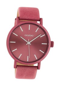 Round OOZOO watch with a matte rose gold face, silver hour markers, and a pink leather strap. Simple design with minimalist accents.
