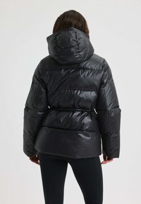 Zwarte pufferjack met capuchon, met een glanzende afwerking, geborduurd ontwerp, riem in de taille en lange mouwen.