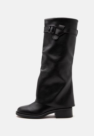 Botte mi-mollet en cuir noir avec un petit talon bloc et une sangle décorative avec boucle autour de la tige supérieure.