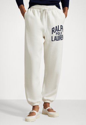 Baltas sporta bikses ar auklu jostas daļā, kurām ir liels tumši zils "RALPH LAUREN" logo. Ar piegrieztiem maliņām un mīkstu, strukturētu audumu.