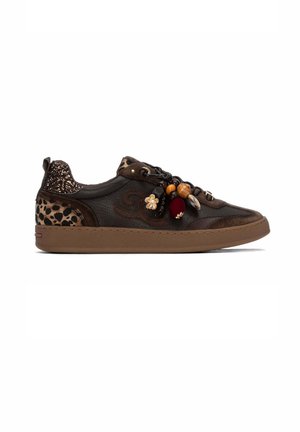 Zapatilla deportiva de cuero marrón oscuro con detalles de estampado de leopardo, cuentas decorativas y amuletos en los cordones, y suela de goma marrón.