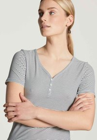 Korte mouwen, V-hals t-shirt in het wit met marineblauwe strepen, met drie knopen bij de hals en een getailleerd ontwerp. Soepele katoen textuur.