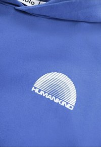 Hoodie blu in morbido tessuto con una grafica bianca caratterizzata da linee orizzontali e la parola "HUMANKIND" sotto un design a mezzaluna.