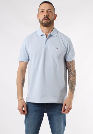 Polo shirt azzurro chiaro in cotone, con colletto classico, maniche corte e un sottile dettaglio del logo sul petto. Abbinato a jeans di denim.