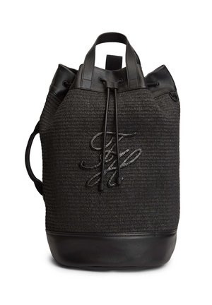 Mochila negra tejida con ribetes de cuero, cierre de cordón, asas superiores y logo en relieve de letras en la parte frontal.