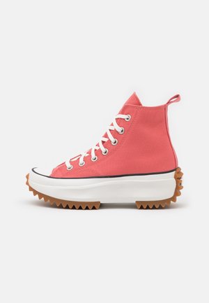 Højtop koral canvas-sneaker med hvide snørebånd, tyk hvid platformsål og brun takket gummiydersål for godt greb.