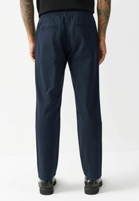 Marineblaue, leichte Hose mit einem elastischen Bund, zwei Gesäßtaschen und einer glatten Textur. Geeignet für Freizeitkleidung.