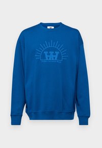 Blue sweatshirt made of soft fabric, featuring a round neckline, drop shoulders, and a front graphic with a sunburst design.