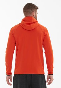 Heren oranje hoodie, lichtgewicht stof, lange mouwen, met een ruime capuchon en contrasterende zwarte rand bij de manchetten. Gladde textuur, atletische pasvorm.