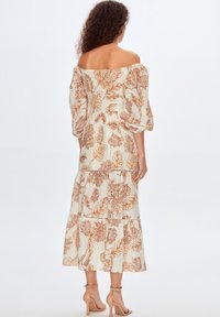 Off-the-shoulder maxikjole i cremefarvet stof med orange blomsterprint, der har pufærmer, lagdelt skørt og flæsedetaljer.