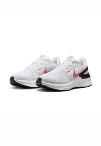 Zapatillas deportivas blancas con acentos en rosa, que presentan una textura de malla, un collar acolchado y una suela exterior negra. Logo de Nike en el lateral y en la lengüeta.