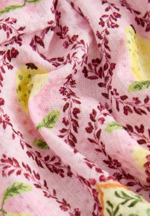 Pink fabric with floral patterns in maroon and green, featuring a soft texture and light draping. The design includes accents of yellow.