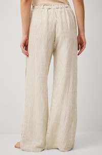 Pantaloni a gamba larga a righe leggeri in tessuto beige e crema, con vita elastica e una finitura morbida e testurizzata.