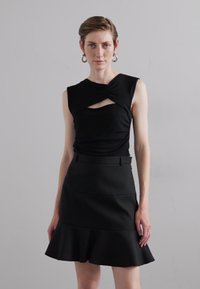 Haut sans manches noir avec découpe en trou de serrure et détails drapés, associé à une jupe évasée noire ajustée. Texture lisse, design minimaliste.