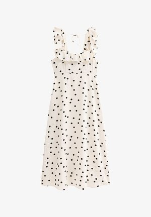 Robe blanche à pois noirs, avec des bretelles froncées et une fermeture à nouer au dos. Tissu lisse, design mi-long et détail de corsage ajusté.