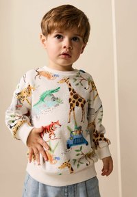 Hvid bomulds-sweatshirt med et farverigt mønster af dyr og en blå bil. Ribkant ved halsudskæring, ærmer og bund. Blød tekstur, afslappet pasform.