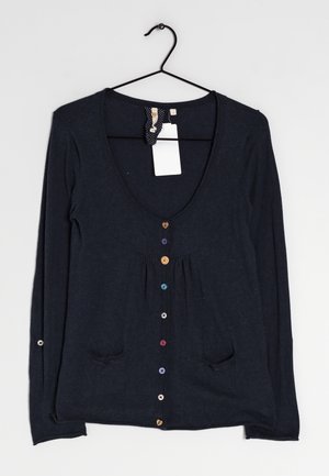 Cardigan bleu marine à manches longues, encolure dégagée profonde, boutons multicolores, deux poches avant, suspendu sur un cintre noir avec des étiquettes attachées.