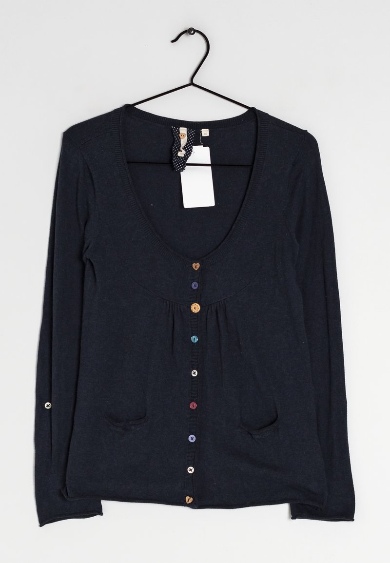 Cardigan bleu marine à manches longues, encolure dégagée profonde, boutons multicolores, deux poches avant, suspendu sur un cintre noir avec des étiquettes attachées.