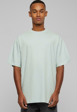 T-shirt oversize vert menthe clair en tissu doux. Il présente des manches courtes, un col rond et une coupe décontractée.