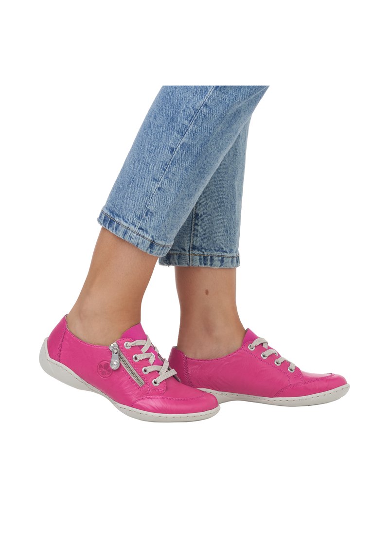 Pink leather sneakers with grey laces, white rubber soles, and a decorative zipper detail. The shoes feature a rounded toe and smooth texture.