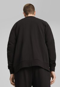 Sort sweatshirt med en afslappet pasform, ribbet rund halsudskæring og store dropped shoulders. Stoffet ser blødt og teksturelt ud.