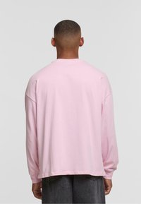 Lange mouwen roze T-shirt van katoen, met een ontspannen pasvorm en afgezakte schouders. Achteraan is er geen bedrukking of patroon te zien.