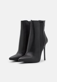 Czarne sk�órzane botki za kostkę z ostrym noskiem, obcasem typu stiletto i elastycznymi panelami bocznymi ułatwiającymi zakładanie. Gładka powierzchnia i elegancki design.