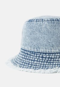 Denim kalap, világoskék és sötétkék kockás mintával, puha tapintással, széles karimával és rojtos széllel.