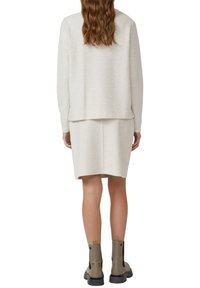 Lichtbeige gebreide trui en rok set met een ontspannen pasvorm. Voorzien van lange mouwen en een rechte zoom. Gecombineerd met taupekleurige enkellaarsjes.