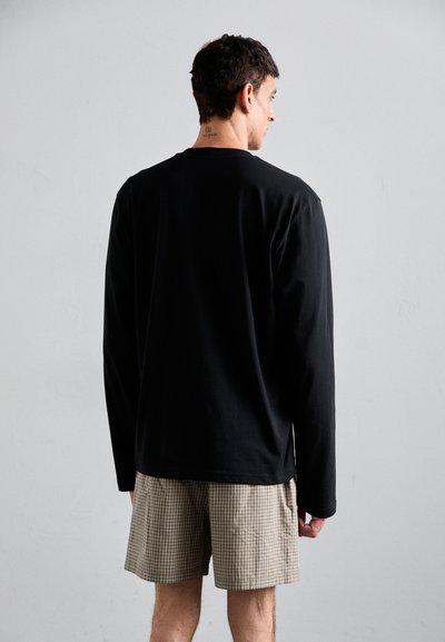 Svart langermet skjorte laget av bomull, kombinert med brune rutete shorts. Skjorten har en ledig passform og en enkel sømfinish.