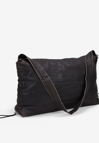 Bolso de hombro de cuero marrón con una textura suave, forma rectangular, correas largas y un diseño discreto. Detalle de cierre con cremallera visible.