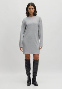 Graues geripptes Strickkleid mit langen Ärmeln, mittlerer Länge und geradem Schnitt, kombiniert mit kniehohen schwarzen Lederstiefeln.