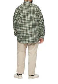 Herenplaid shirt in groene en blauwe tinten; relaxte pasvorm, zachte stof; gedragen met lichtgekleurde corduroypantalon en casual sneakers.