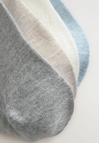 Fire par sokker i grå, lys beige, hvid og lyseblå. De har et blødt, tekstureret stof og et lavt snit.