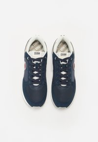 Sneakers blu navy realizzati in mesh e suede, con suola bianca, lacci neri e un accento del logo rosso. L'interno presenta un tessuto di marca.