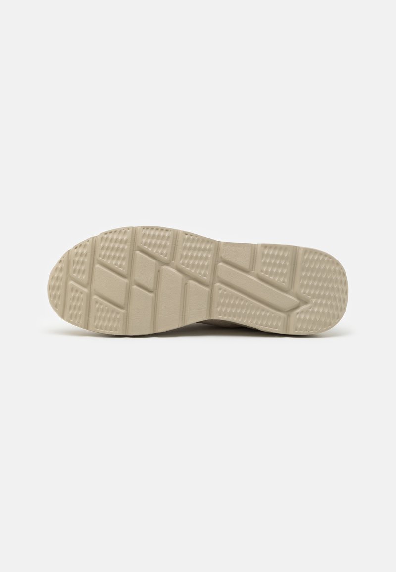 Semelle de chaussure avec un design texturé, affichant une couleur beige clair et plusieurs sections de motifs pour l'adhérence et le soutien.