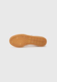 Rubber shoe sole with a textured pattern, featuring a honey-colored finish. Includes circular detail and multi-directional grip design.