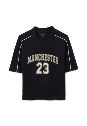 Zwart polo-shirt met korte mouwen, voorzien van witte biezen en de tekst "MANCHESTER" met het nummer "23" in een contrasterend lettertype. Textuurstof.